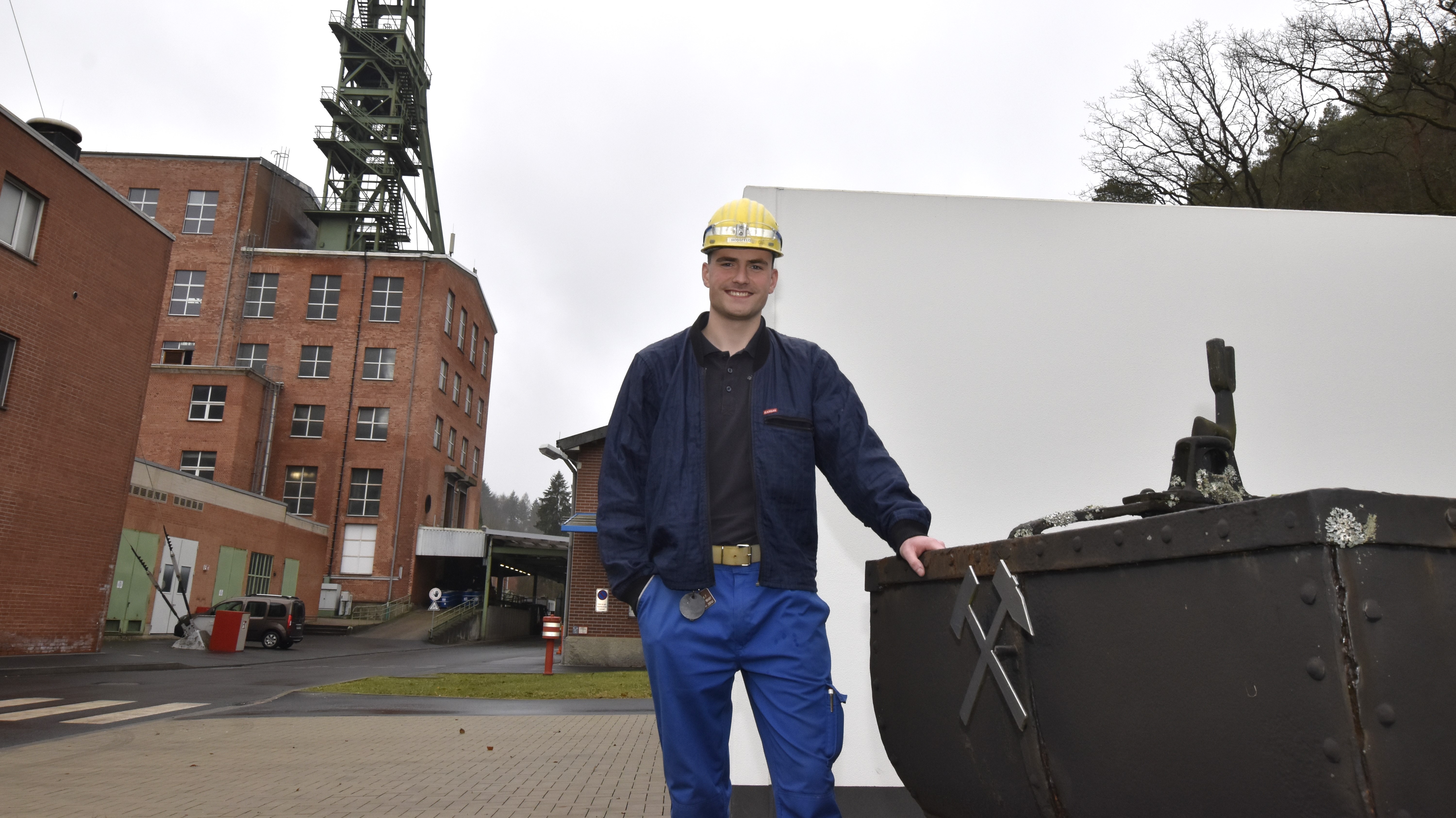 Der Bergbautechnologe Florian Hoßfeld steht vor der Lore und dem Fördergerüst.