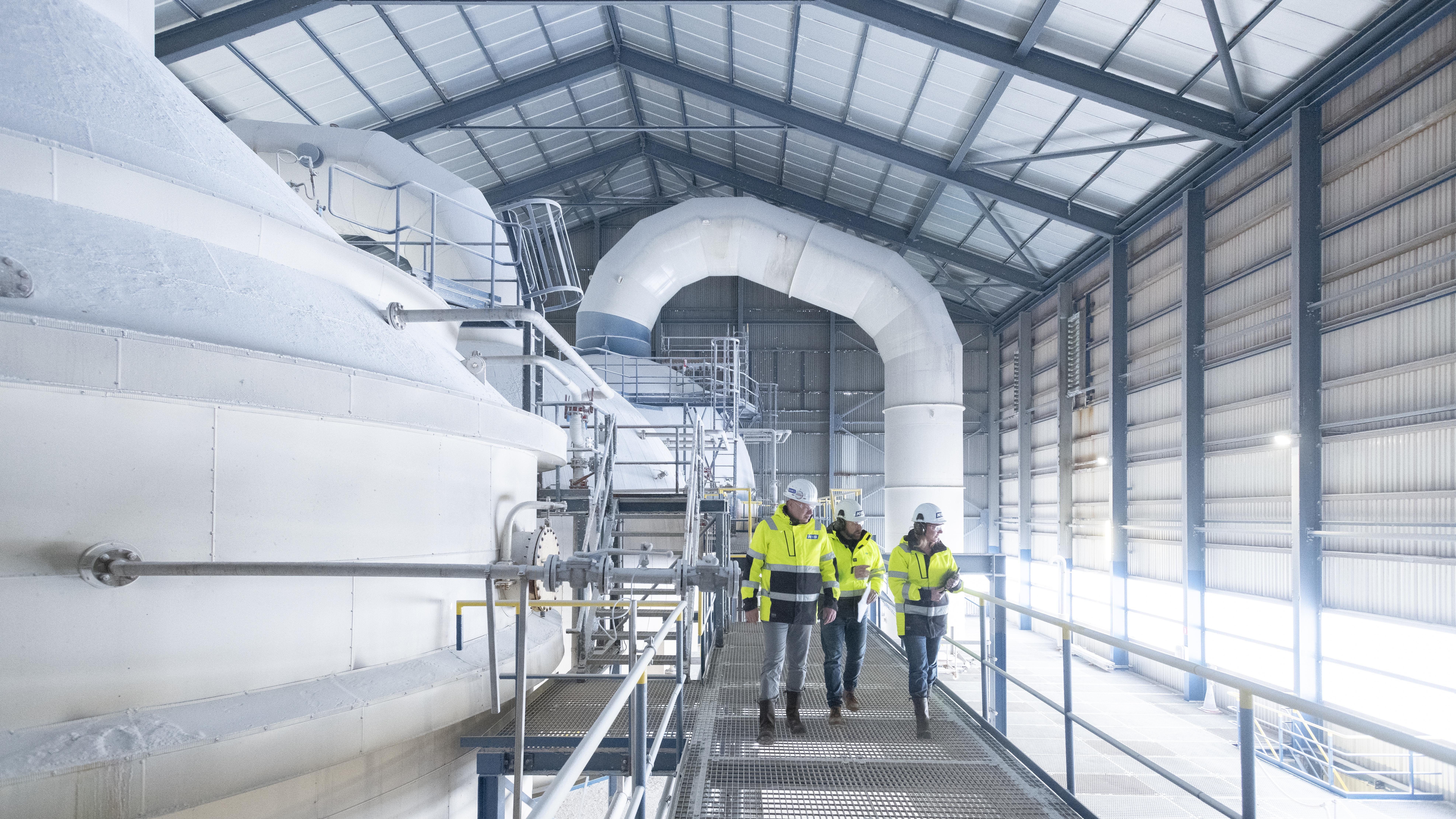 Three employees walk across scaffolding in a factory in Harlingen 